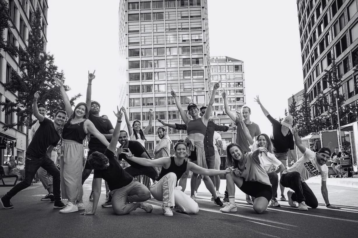 Dance crew smiling and posing together after a flashmob performance in Zurich city centre.