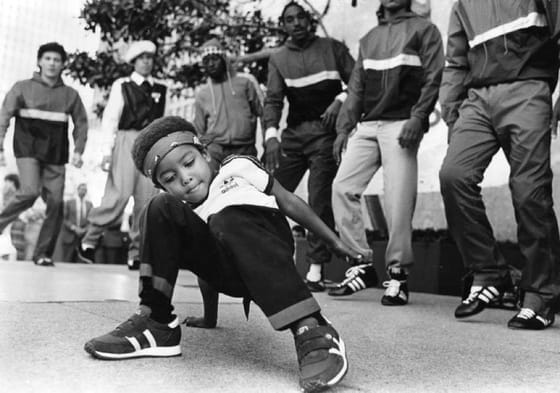 Young boy passionately dancing on the street with other dancers in the background, symbolizing the passion and energy fostered in The Vibe Dance Studio's kids and teens dance classes, including Dance, Hip Hop, and Jazz.