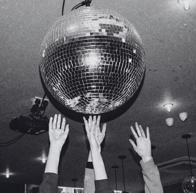 Raised hands under a disco ball, capturing the vibrant atmosphere that can be created within our spacious and versatile dance studio rental space, ideal for various events and creative projects.